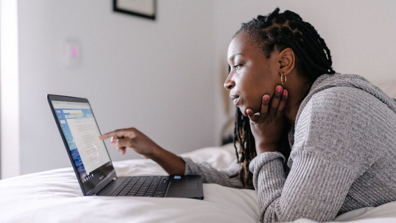 Black woman reading an email on her laptop.